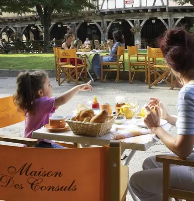 a woman and a little girl sitting at a table with food at La Maison des Consuls in Mirepoix