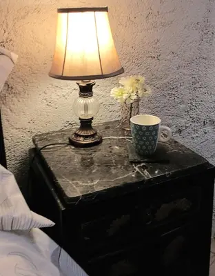 a table with a lamp and a cup on it at Maison de Textile in Montolieu