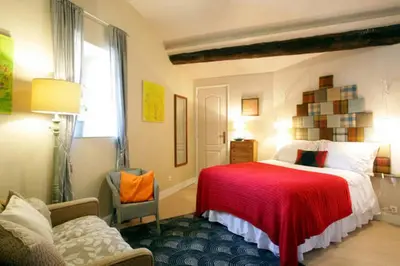 a bedroom with a bed with a red blanket at Maison de Textile in Montolieu