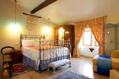 a bedroom with a bed and a chair at Maison de Textile in Montolieu