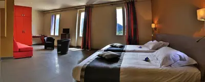 a hotel room with two beds and a red chair at Logis auberge restaurant Du Vigneron in Cucugnan