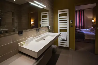 a bathroom with a sink and a mirror and a bed at Logis auberge restaurant Du Vigneron in Cucugnan