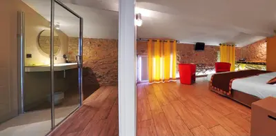 a bedroom with a bed and a bathroom with a mirror at Logis auberge restaurant Du Vigneron in Cucugnan