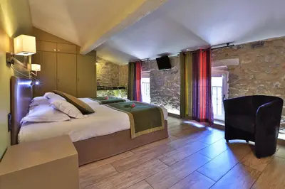 a bedroom with a bed and a table and a chair at Logis auberge restaurant Du Vigneron in Cucugnan