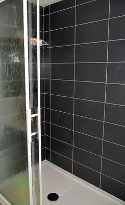 a shower with a black tiled wall at Logis Hotels - Hôtel et Restaurant de la Montagne Noire in Dourgne