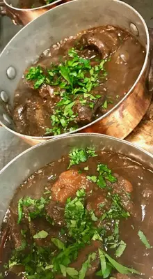 two metal pots of food with meat and herbs at Logis Hotels - Hôtel et Restaurant de la Montagne Noire in Dourgne