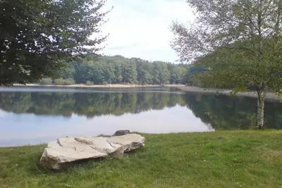 a rock sitting in the grass next to a lake at Logis Hotels - Hôtel et Restaurant de la Montagne Noire in Dourgne
