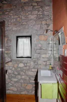 a stone bathroom with a sink and a window at Moulin d'entre les roches in Puivert