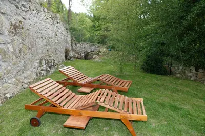 two wooden chairs and a picnic table in the grass at Moulin d'entre les roches in Puivert