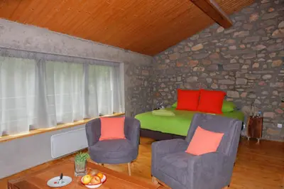 a living room with two chairs and a bed at Moulin d'entre les roches in Puivert