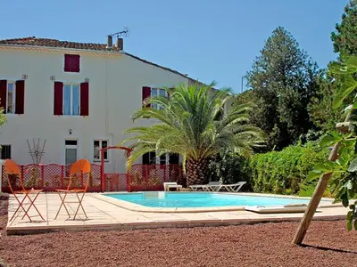 a swimming pool with two chairs and a house at La Vadrouille in Sigean