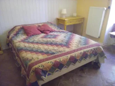 a bed with a quilt and a night stand and a table at La Vadrouille in Sigean