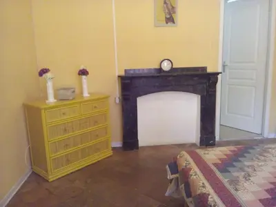 a room with a fireplace and a dresser with a clock at La Vadrouille in Sigean