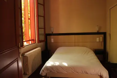 a bedroom with a white bed and a window at Hôtel Le Commerce in Mirepoix