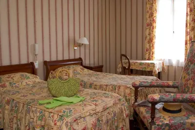 a room with two beds and aulture sitting on the bed at Hôtel Le Commerce in Mirepoix