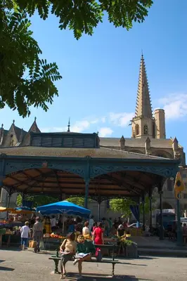 a group of people sitting on benches in a market at Hôtel Le Commerce in Mirepoix
