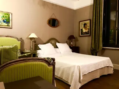 a bedroom with a bed and a green chair at Villa Limonade, maison d'hotes in Olonzac