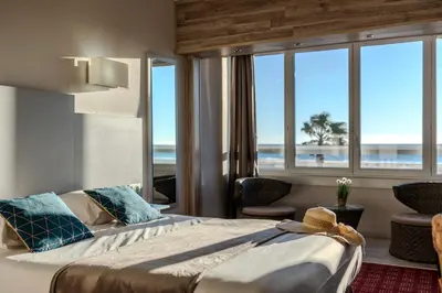 a bedroom with a bed with a view of the ocean at Logis Hôtel & Restaurant Mediterranee in Port-la-Nouvelle