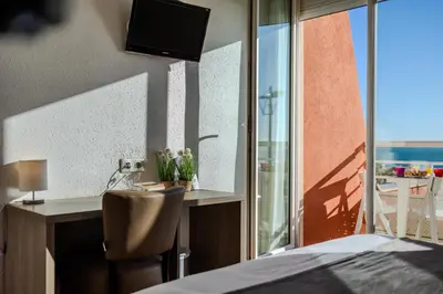 a bedroom with a desk and a bed and a window at Logis Hôtel & Restaurant Mediterranee in Port-la-Nouvelle