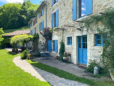 a stone house with blue doors and a yard at Nabat le Haut, chambre et table d'hotes in Courniou