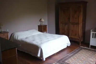 a bedroom with a bed and a wooden cabinet at Nabat le Haut, chambre et table d'hotes in Courniou