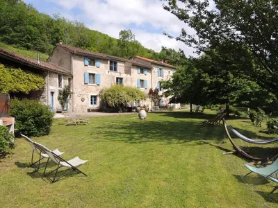 a yard with two chairs and a building at Nabat le Haut, chambre et table d'hotes in Courniou