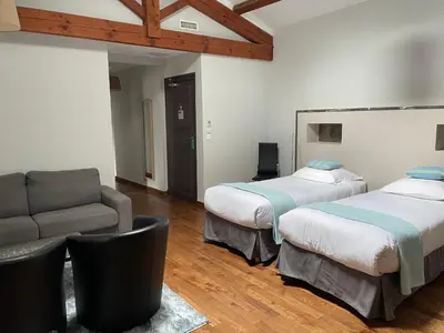 a room with two beds and a couch and a chair at Logis Hôtel Château De Palaja in Carcassonne