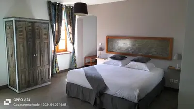 a bedroom with a large bed and a large window at Logis Hôtel Château De Palaja in Carcassonne