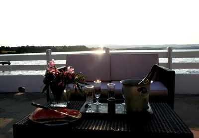 a table with two glasses and flowers on a balcony at Maison de pecheur in Sigean