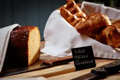 a table topped with bread and pastries on a cutting board at Auberge du Poids Public Logis Hotel in Saint-Félix-Lauragais