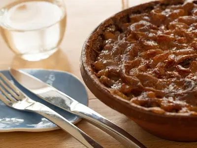 a pie sitting on a table next to a glass of water at Auberge du Poids Public Logis Hotel in Saint-Félix-Lauragais