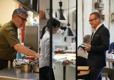 a man and a woman preparing food in a kitchen at Auberge du Poids Public Logis Hotel in Saint-Félix-Lauragais