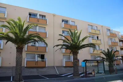 two palm trees in front of a building at Gites de France Bleu à la mer in Port-la-Nouvelle