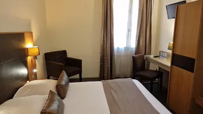a hotel room with a bed and a desk at Hotel Restaurant du Centre et du Lauragais in Castelnaudary