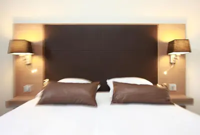 a bedroom with a large white bed with two pillows at Hotel Restaurant du Centre et du Lauragais in Castelnaudary