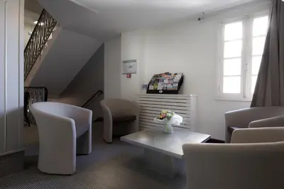 a living room with white chairs and a table at Hotel Restaurant du Centre et du Lauragais in Castelnaudary