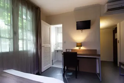 a room with a desk and a television on the wall at Hotel Restaurant du Centre et du Lauragais in Castelnaudary