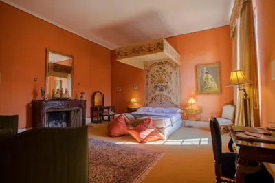a bedroom with orange walls and a bed and a fireplace at Château de Floure - SPA et piscine extérieure chauffée in Carcassonne
