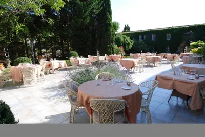 an outdoor patio with tables and chairs and tablesearcher at Château de Floure - SPA et piscine extérieure chauffée in Carcassonne