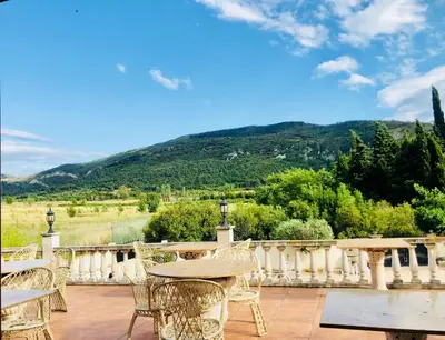 a patio with tables and chairs and mountains in the background at Château de Floure - SPA et piscine extérieure chauffée in Carcassonne