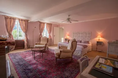 a bedroom with a bed and two chairs and a table at Château de Floure - SPA et piscine extérieure chauffée in Carcassonne