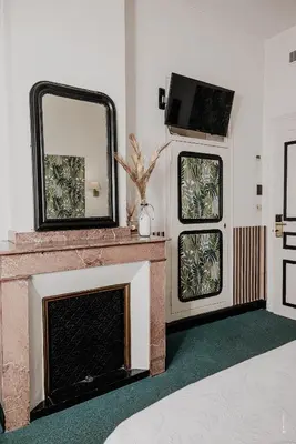 a living room with a fireplace and a mirror at Hotel Moderne Et Pigeon in Limoux