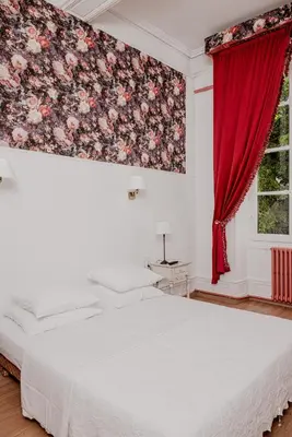 a bedroom with a bed and a red curtain at Hotel Moderne Et Pigeon in Limoux