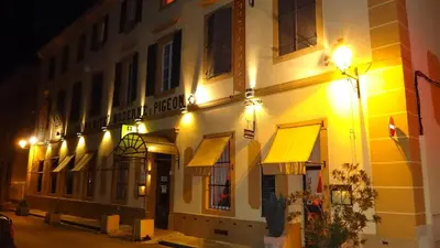 a building with yellow awnings on a street at night at Hotel Moderne Et Pigeon in Limoux