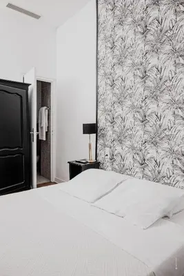 a bedroom with a white bed with a tropical wallpaper at Hotel Moderne Et Pigeon in Limoux