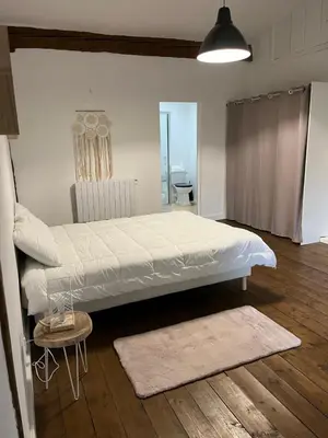 a bedroom with a large white bed and a wooden floor at Domaine Saladry in Villepinte