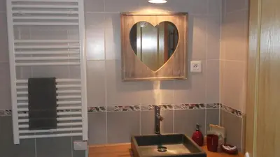a bathroom with a sink and a heart mirror at La Grange d'Antan in Cruzy