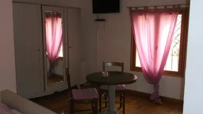 a table and chairs in a room with pink curtains at La Grange d'Antan in Cruzy