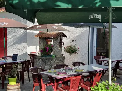 a group of tables and chairs with umbrellas on a patio at Hotel Ô Fil de L'ô in Marseillette
