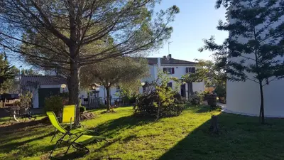a white house with a yard with chairs and trees at Hotel Ô Fil de L'ô in Marseillette